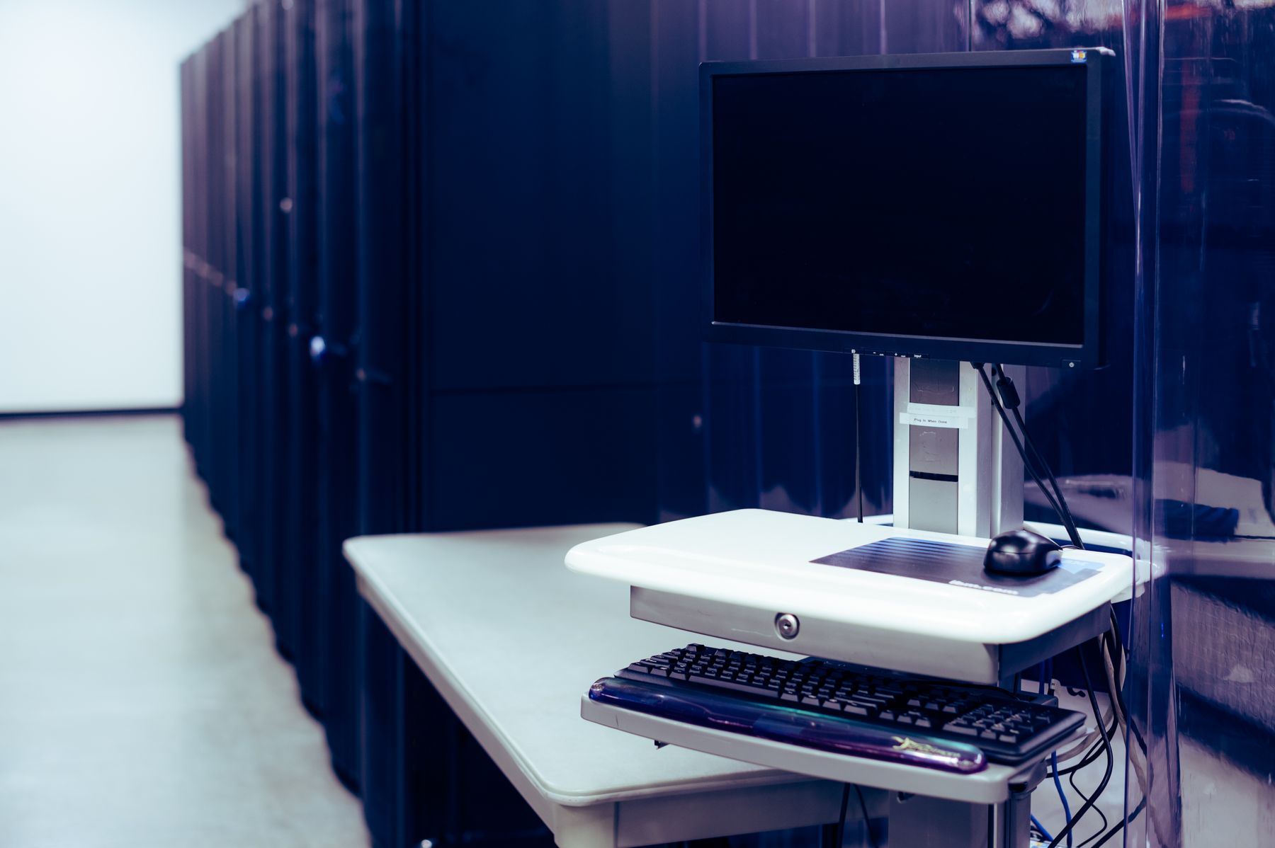 A computer terminal alongside server racks in a data centre