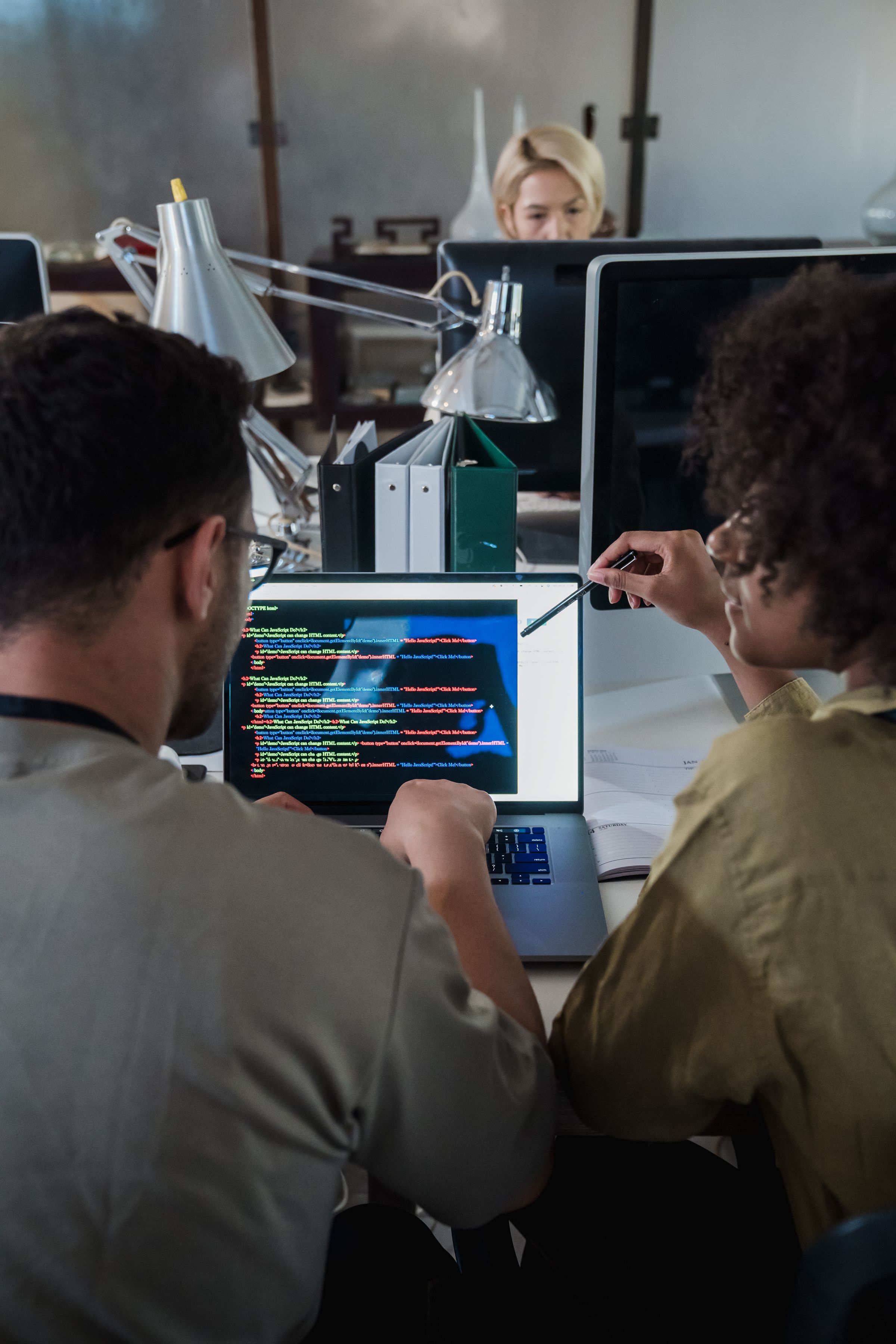Colleagues discussing software on a laptop in a shared workspace